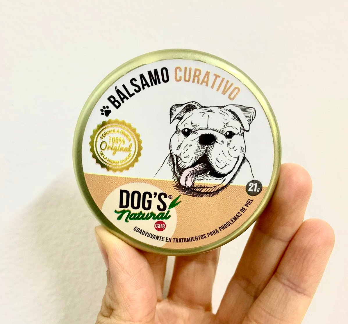 el Bálsamo curativo para perros de dogs natural care version 21g en la mano de una mujer con fondo blanco 