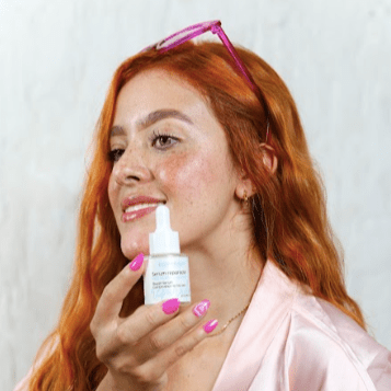 una mujer con el Sérum Facial Reparador Piel Mixta de Botanikalia en su manos cerca su cara. 