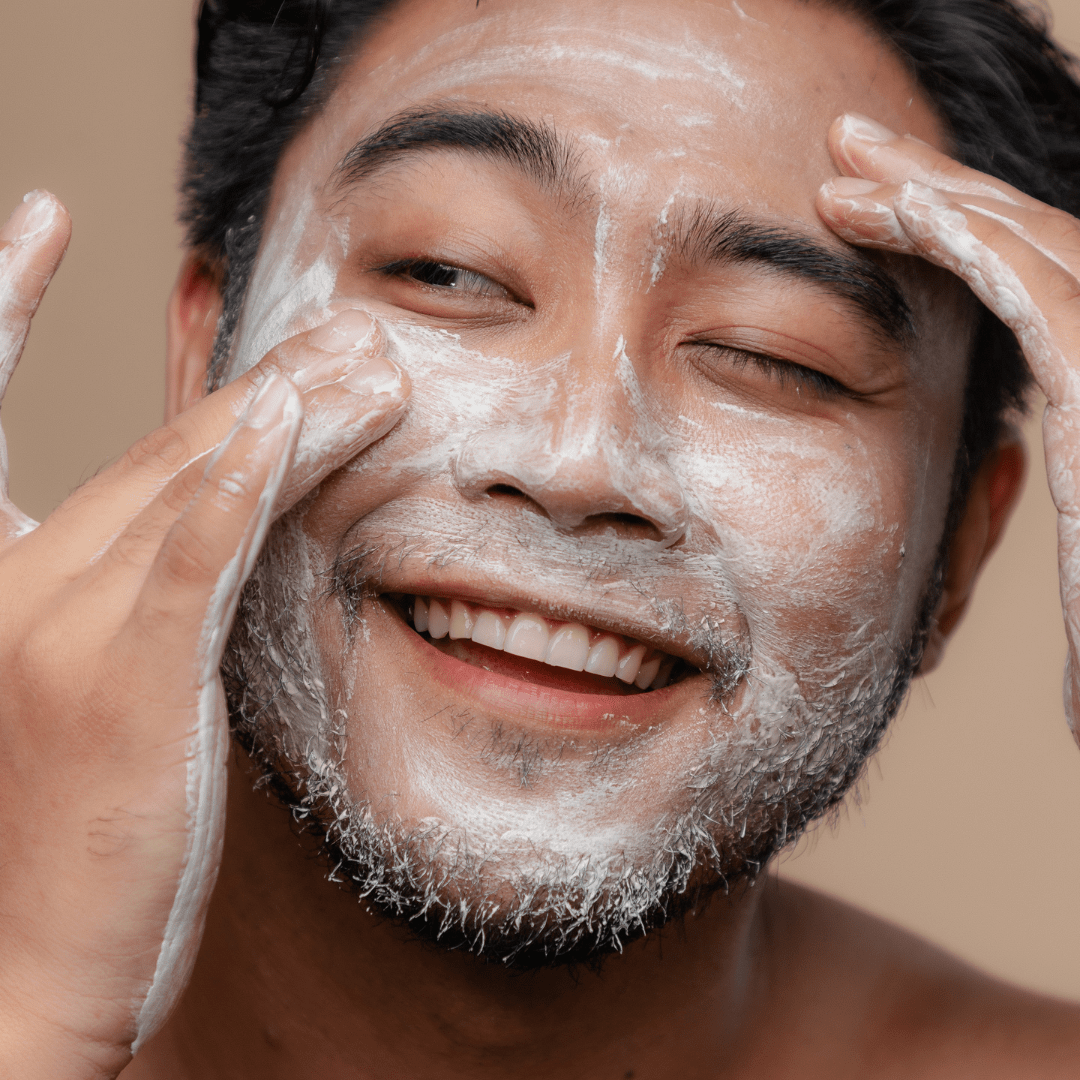 un hombre aplicando el jabon para afeitar en su barba y cara. 