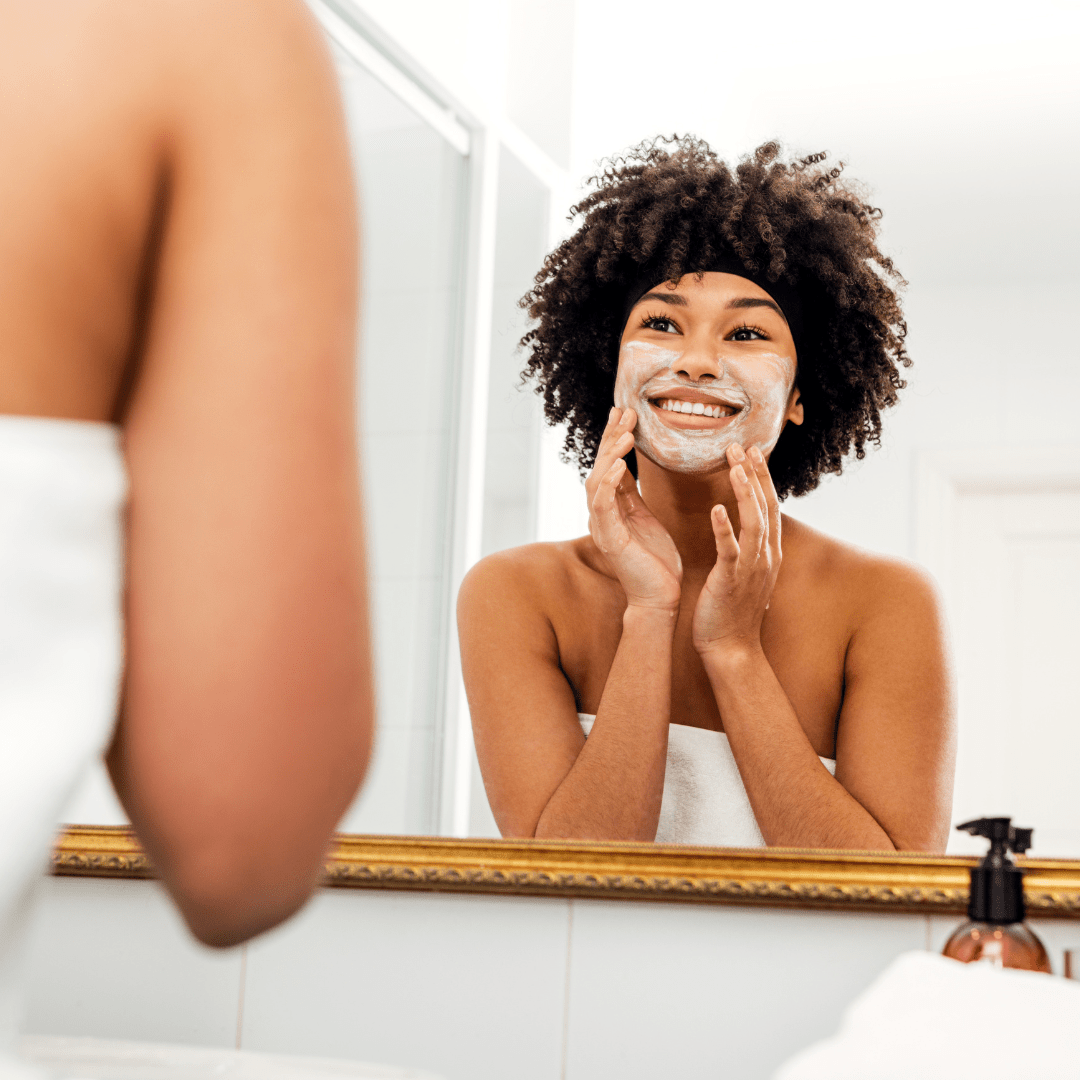 una mujer mirando el espejo y usando el jabón facial en su cara 