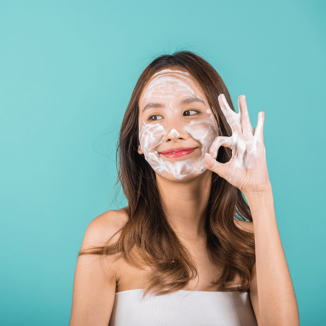 una mujer usando el jabón facial en su cara sonriendo 