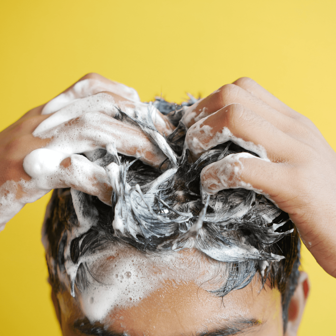 un chico usando el acondicionador en barra de kanawii en su cabello.