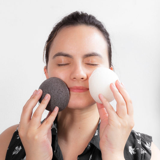 dos Esponjas exfoliantes de Konjac en los manos de una mujer aplicándolo a su cara. 